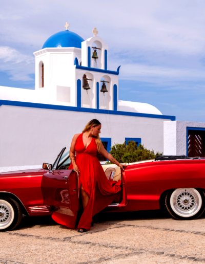 Red flying dress photoshoot in Santorini at a blue-domed church with our vintage car